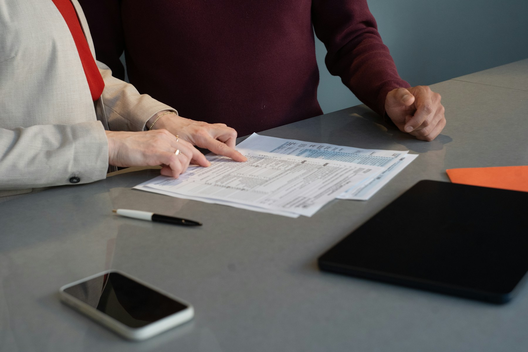 Hands across a desk reviewing home loan paperwork.